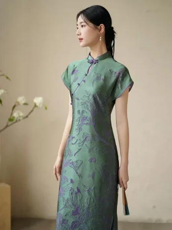 Side view of women's green modified qipao dress, short sleeve floral pattern cheongsam with 3D cut flower craft fabric, highlighting the elegant slim fit and smooth drape