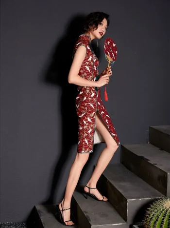 Side view of a woman walking down stairs in a red modern crane print cotton cheongsam dress, highlighting the high side slit and elegant silhouette of this classic short cheongsam style.