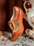 Close-up of a single vintage genuine leather qipao shoe, featuring 1920s ribbon mary jane design, smooth brown leather, and delicate butterfly ribbon, styled with an antique vase for an elegant retro aesthetic