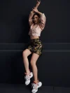 Full-body shot of a woman styling the ink black tiger jacquard A-line short skirt with a pink traditional top and sneakers, highlighting the skirt's high waist and vibrant tiger jacquard pattern; versatile black short skirt for casual-chic looks