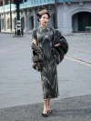 Full-body shot of a woman wearing a dark green brown tone 1930s long mulberry silk qipao, paired with a fur stole and pearl earrings, standing on a retro Shanghai street to show the dress's elegant lines and high slit.