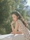 Vintage film aesthetic cotton qipao dress, woman in red polka dot cap sleeve qipao leaning on balcony railing, midcentury Hong Kong style daily wear