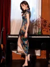 Model wearing Chinese vintage floral pattern silk qipao dress, side view showcasing the high slit design, silky fabric sheen, and elegant fit against a retro piano background.