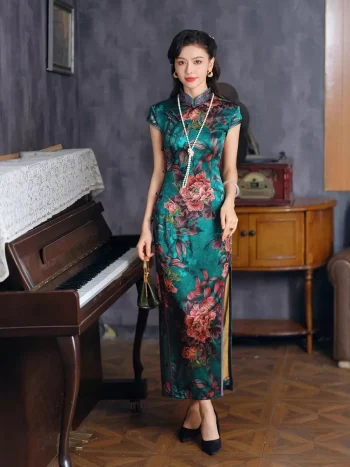 Full-length front view of women's vintage green silk qipao with peony print, model standing by piano in retro interior