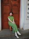 White 1920s Qipao dress goat leather shoes with classic cutout details, worn with a green vintage cheongsam by a model sitting at Duolun Road, capturing 1920s Shanghai cheongsam style.