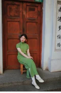 White 1920s Qipao dress goat leather shoes with classic cutout details, worn with a green vintage cheongsam by a model sitting at Duolun Road, capturing 1920s Shanghai cheongsam style.