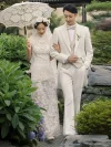 White Lace Qipao Wedding Dress - Bride in a vintage modified white lace qipao walking arm-in-arm with groom in a white suit, holding a lace parasol in a traditional Chinese garden, featuring cap sleeves, lace overlay, and classic silhouette for timeless wedding photos.