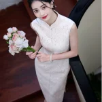 Top view of a woman wearing a white lace modern sleeveless cheongsam dress, holding a bouquet of flowers while standing on wooden stairs, showcasing the elegant lace texture and form-fitting silhouette.