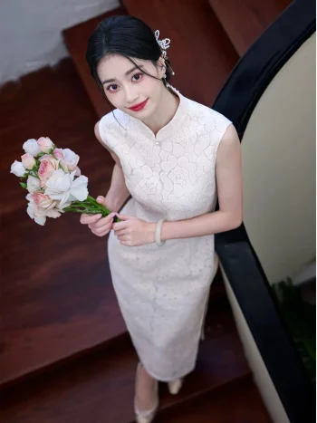 Top view of a woman wearing a white lace modern sleeveless cheongsam dress, holding a bouquet of flowers while standing on wooden stairs, showcasing the elegant lace texture and form-fitting silhouette.
