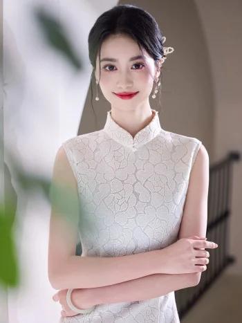 Close-up portrait of a woman in a white lace cheongsam dress with arms crossed, highlighting the intricate lace pattern, high mandarin collar, and delicate bead details on the neckline.