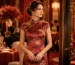 Elegant white woman wearing a red floral silk qipao at a formal Chinese wedding banquet with festive red decor.