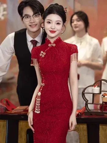 Bride wearing a wine red floral lace chinese wedding cheongsam dress, elegant midi cheongsam with traditional tassel and pearl details, posing at a classic chinese wedding ceremony.