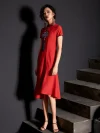 Elegant woman standing in a modern modified red cheongsam dress with handcrafted embroidery and tassel, showcasing midi length and slim fit design.