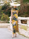 Full-body shot of a model walking outdoors in a women high end yellow mulberry silk cheongsam dress with vibrant landscape print, showing the elegant long silhouette.