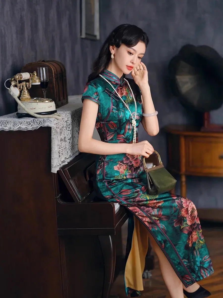women-vintage-green-printed-silk-long-qipao-model-seated-piano Model wearing vintage green printed silk long qipao seated on piano in retro room, elegant traditional Chinese dress with peony print