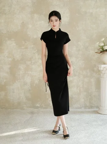 A woman wearing a black slim fit qipao dress stands facing the camera. This elegant women qipao features a classic stand collar with a keyhole cutout, side drawstring detail, and a flowing silhouette.