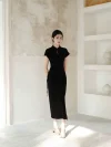 Full length shot of a woman in a black slim fit qipao dress, standing in a minimalist indoor space. The women qipao’s high side slit and sleek fit create a sophisticated look.