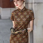 Side view of a women's checkered long cheongsam, an Old Shanghai style qipao dress. The model leans against a stone wall, holding a wooden hand fan, showcasing the tailored silhouette, high stand-up collar, and intricate checkered pattern in rich brown, black, and warm tones, styled with lace gloves and period jewelry.