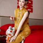 Modern Chinese Yellow Cheongsam Wedding Dress - Bride in brocade cheongsam sitting on red bed holding lion dance toy, cheerful qipao with pearl tassels for traditional chinese weddings