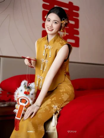 Modern Chinese Yellow Cheongsam Wedding Dress - Bride in brocade cheongsam sitting on red bed holding lion dance toy, cheerful qipao with pearl tassels for traditional chinese weddings