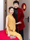 Modern Chinese Yellow Cheongsam Wedding Dress - Bride in elegant brocade cheongsam posing with family member, sleeveless two-piece qipao with pearl tassels, traditional chinese wedding outfit