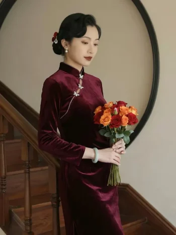 Elegant oriental lady wears tailored Velvet Long Sleeve Burgundy Cheongsam decorated with silver butterfly frog buttons, holding fresh red-orange roses beside solid wood staircase and round hollow wall frame, premium soft Cheongsam Velvet long sleeve cheongsam for retro formal outfit
