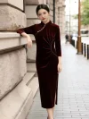 Stylish chinese woman wears ruched waist Velvet Long Sleeve Burgundy Cheongsam with classic mandarin collar, leaning elbow on vintage european stone building wall along city sidewalk, durable premium Cheongsam Velvet mid-length long sleeve cheongsam