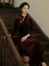 Lady with old-shanghai retro curled updo hairstyle wears slim-fit Long Sleeve Cheongsam made of thick burgundy velvet, sitting leisurely on dark solid wood staircase steps with side high slit design, classy Cheongsam Velvet evening party cheongsam dress