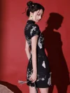 Side angle shot showing the back silhouette of a black mini cheongsam dress with nature-inspired print.