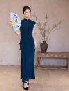 Model holding a painted folding fan wearing a classic blue cheongsam dress, standing against a minimalist beige wall with plum blossoms.