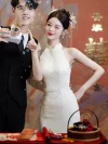 Playful and romantic scene of a stylish bride in a white cheongsam with halter design, smiling and posing next to a groom as they play with a bubble gun in a room decorated with the Chinese 'Double Happiness' sign.