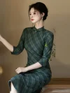 Refined woman seated elegantly in a modern cheongsam dress long sleeve featuring a traditional plaid pattern, looking away thoughtfully in a natural-light room.