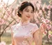 Young woman in a romantic pink qipao dress symbolizing youth, romance, and playfulness, reminiscent of spring peach blossoms