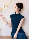 Close-up side profile of a model in a sleek blue qipao dress, reaching out to touch yellow plum blossom branches, highlighting the clean oriental aesthetic.