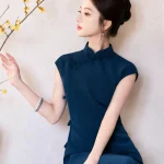 Close-up side profile of a model in a sleek blue qipao dress, reaching out to touch yellow plum blossom branches, highlighting the clean oriental aesthetic.