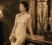 A woman in a 1920s vintage Shanghai-style Cheongsam dress, leaning against a table in a retro interior.