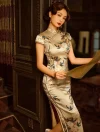 Elegant woman in a yellow silk cheongsam with delicate floral embroidery, leaning against a dark wood door while holding a vintage newspaper.