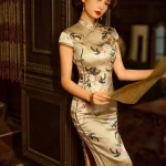 Elegant woman in a yellow silk cheongsam with delicate floral embroidery, leaning against a dark wood door while holding a vintage newspaper.